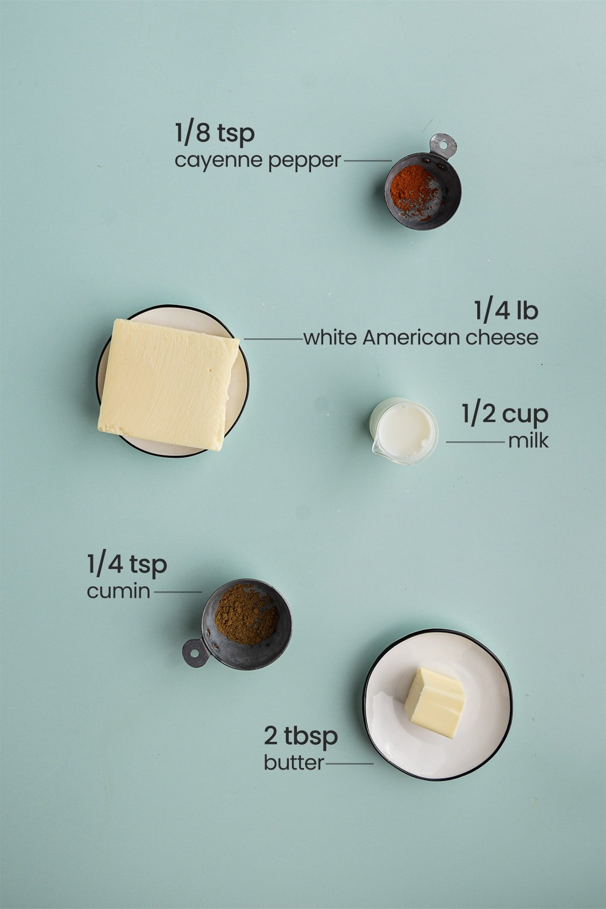 All 5 ingredients for Tex-Mex Queso Blanco including cayenne pepper, white American cheese, milk, cumin, and unsalted butter