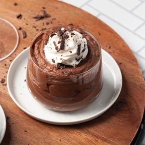 close up of glass filled with boozy chocolate mousse topped with whipped cream and shaved dark chocolate