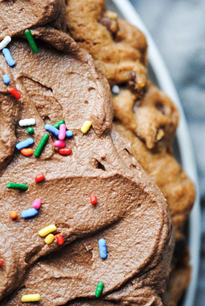 Close up of a cookie cake with chocolate ganache with rainbow sprinkles on top