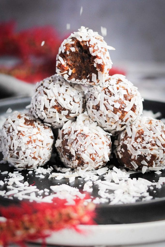 Portrait of coconut covered energy balls with coconut flakes falling on top