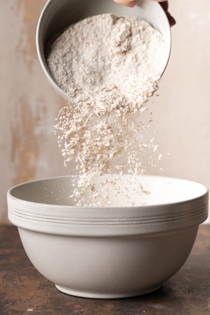 Pouring whole wheat flour into large mixing bowl