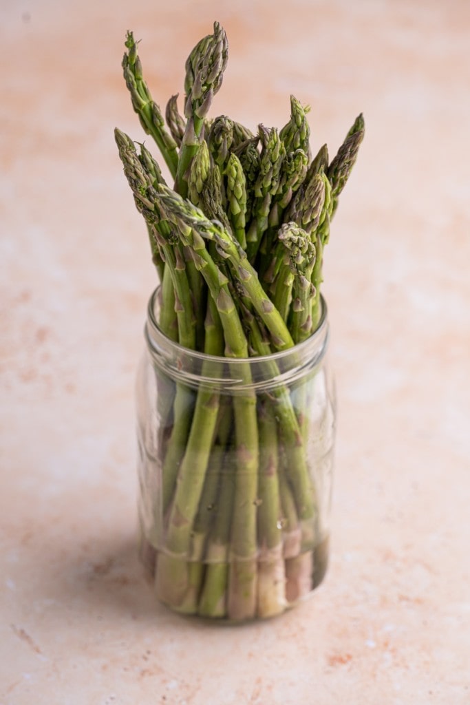 asparagus stored in a mason jar with ends submerged in water