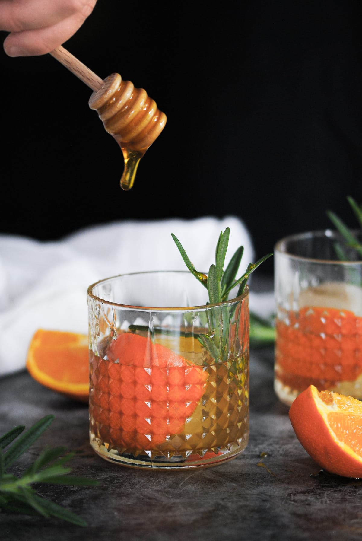 Honey Dripping off of honey dipper into a whiskey cocktail