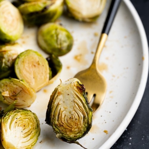 close up of crispy brussels sprout on a black and gold fork