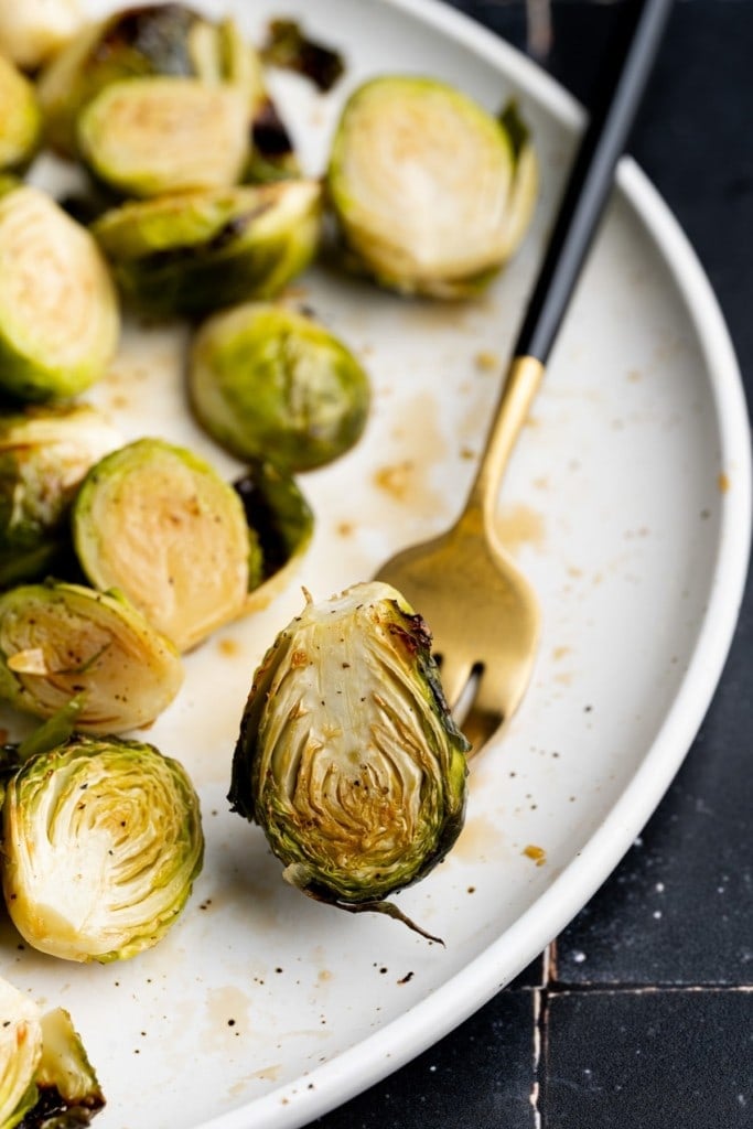 close up of crispy brussels sprout on a black and gold fork