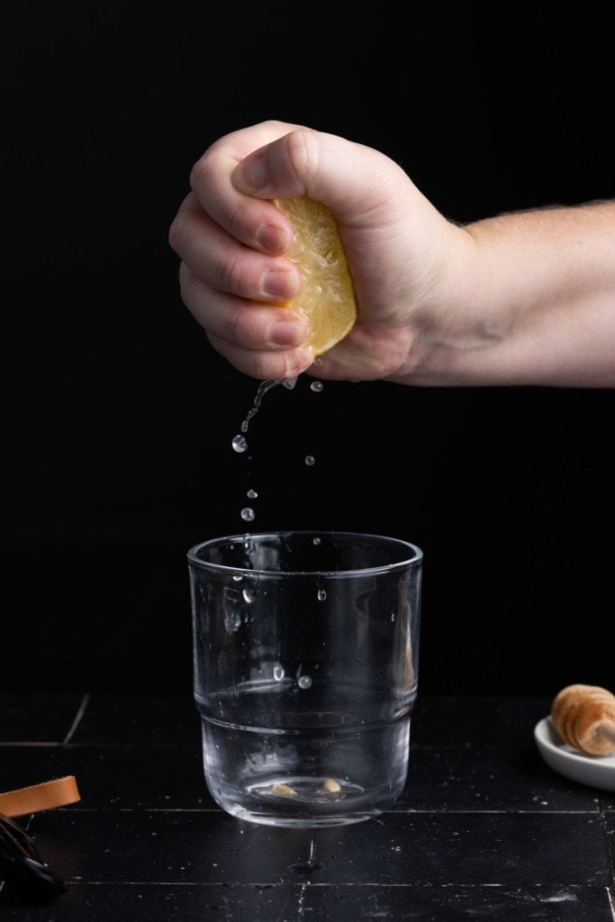 squeezing fresh lemon juice into a cup to make sweet and salty sauce