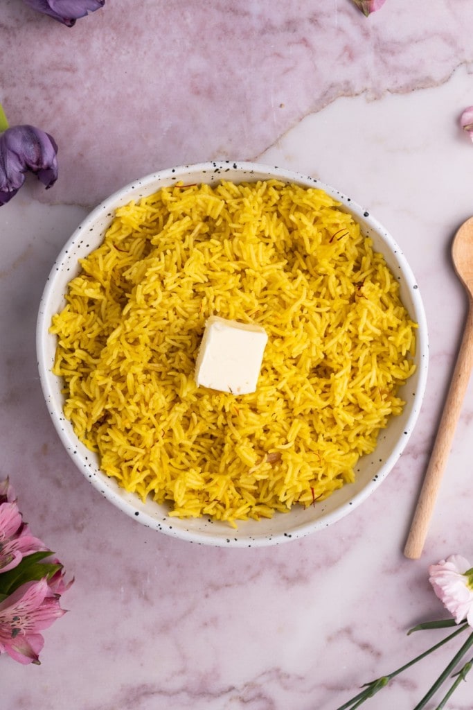 Adding butter to cooked yellow saffron rice
