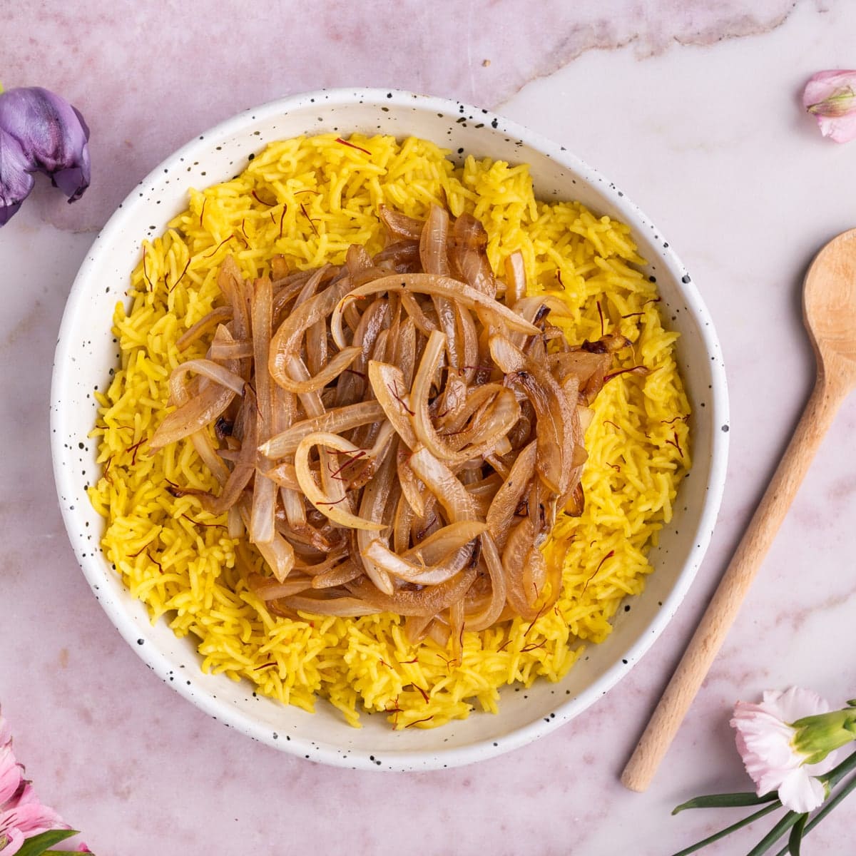 Aromatic Yellow Saffron Rice with Caramelized Onions on a pink marble background