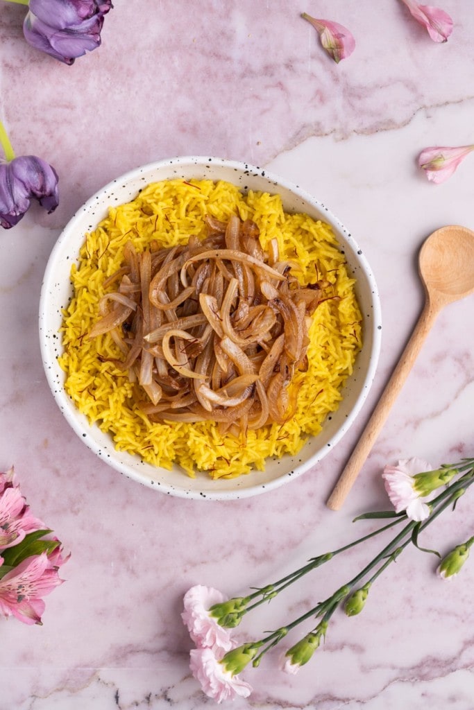 Overhead shot of Saffron Rice with Caramelized Onions with a wooden spoon next to it