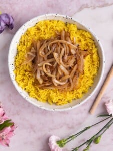 Overhead shot of Saffron Rice with Caramelized Onions with a wooden spoon next to it