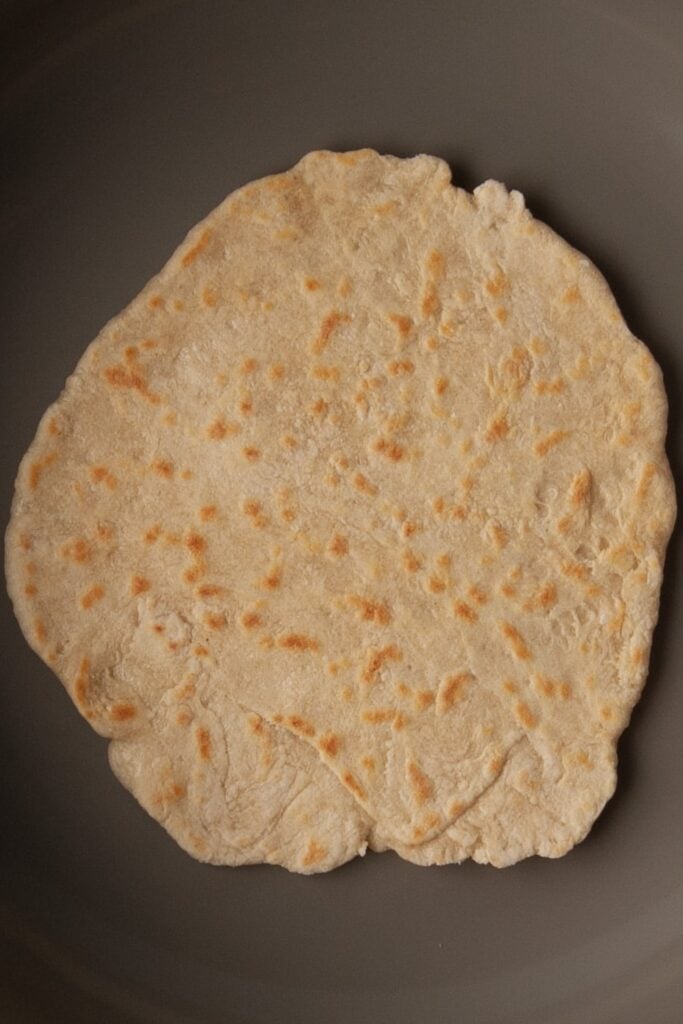 Homemade flour tortillas without lard frying in a pan.