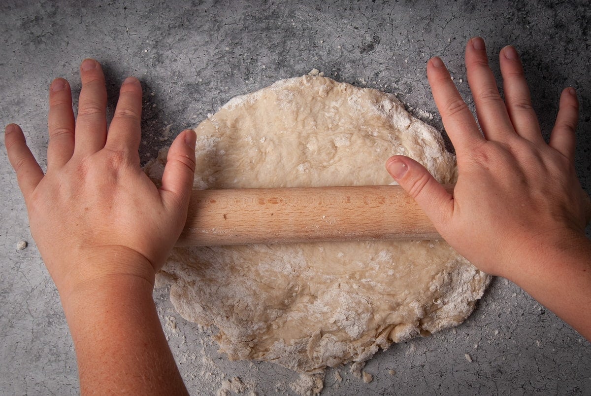 Using a rolling pin to flatten tortilla dough.