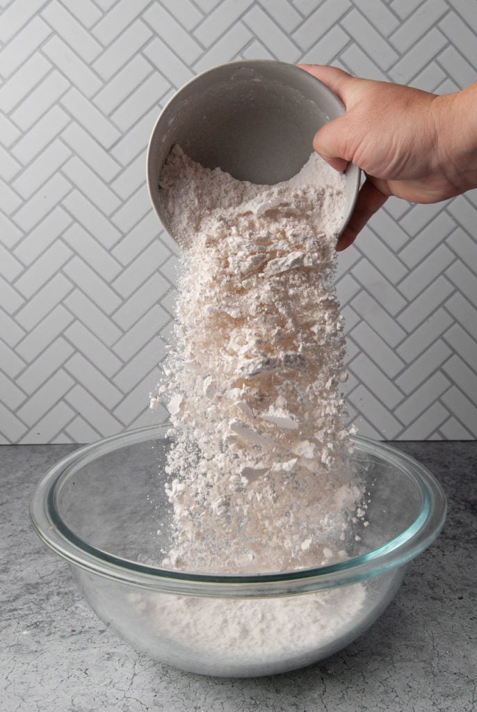 Adding flour to a mixing bowl.