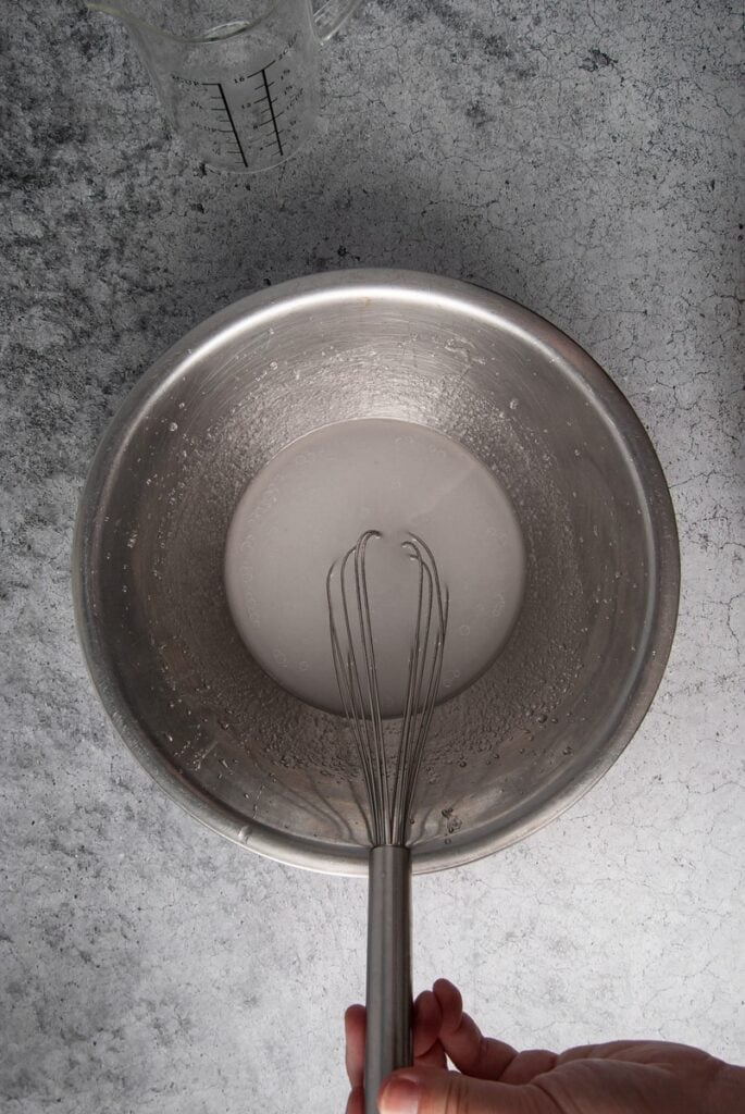 Using a whisk to emulsify water and coconut oil.