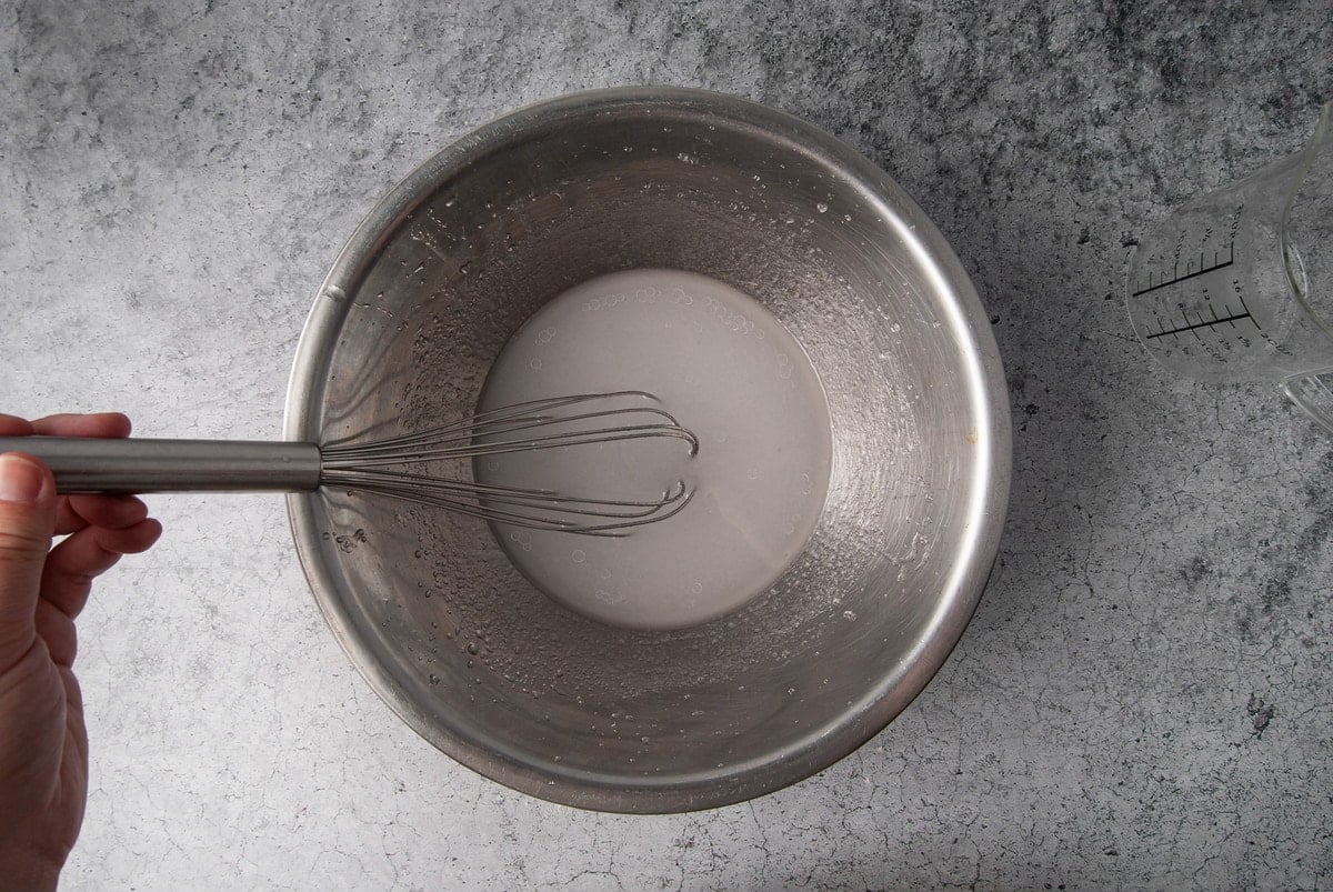 using a whisk to emulsify water and coconut oil