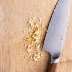 Minced garlic on a cutting board ready to add to Greek Vinaigrette