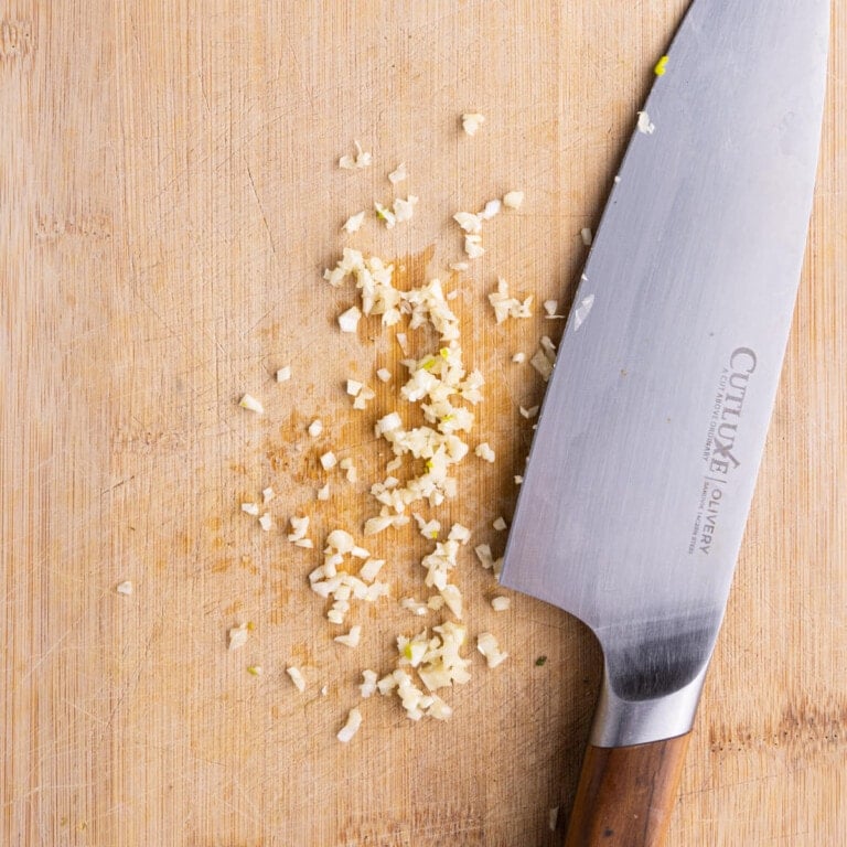 Minced garlic on a cutting board ready to add to Greek Vinaigrette