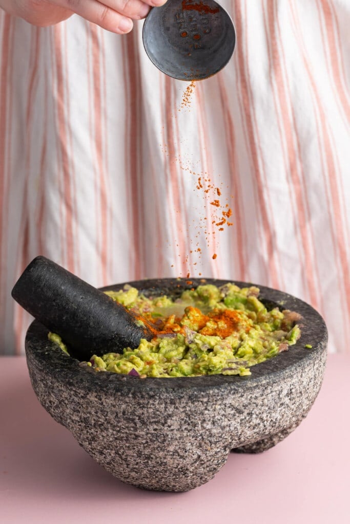 Adding cayenne pepper to guacamole to add spice.