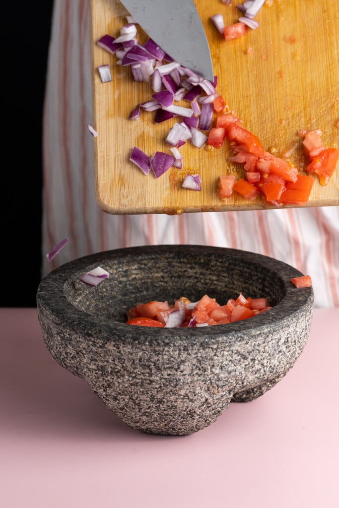 Adding diced tomato and red onion to mortar