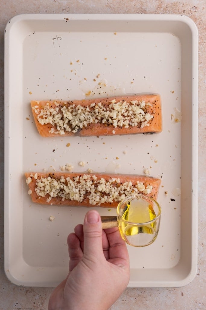 Drizzling olive oil over garlic coated salmon