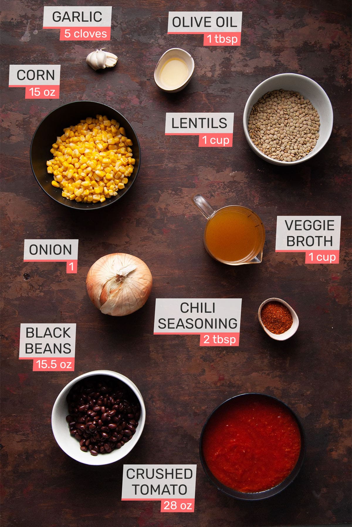 overhead picture of ingredients for vegan chili with lentils - garlic, olive oil, corn, lentils, onion, veggie broth, onion, chili seasoning, black beans and crushed tomato