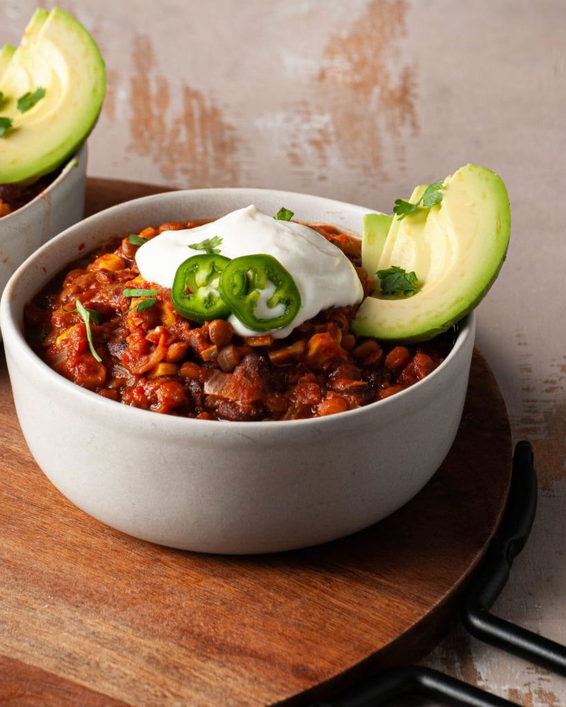 bowl of southwestern chili with sour cream , jalapeno, and avocado