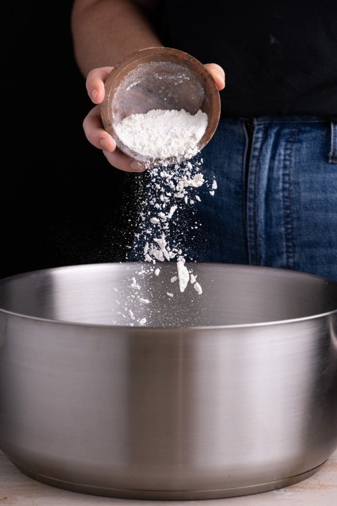 Adding all-purpose flour to a large pot to forma roux