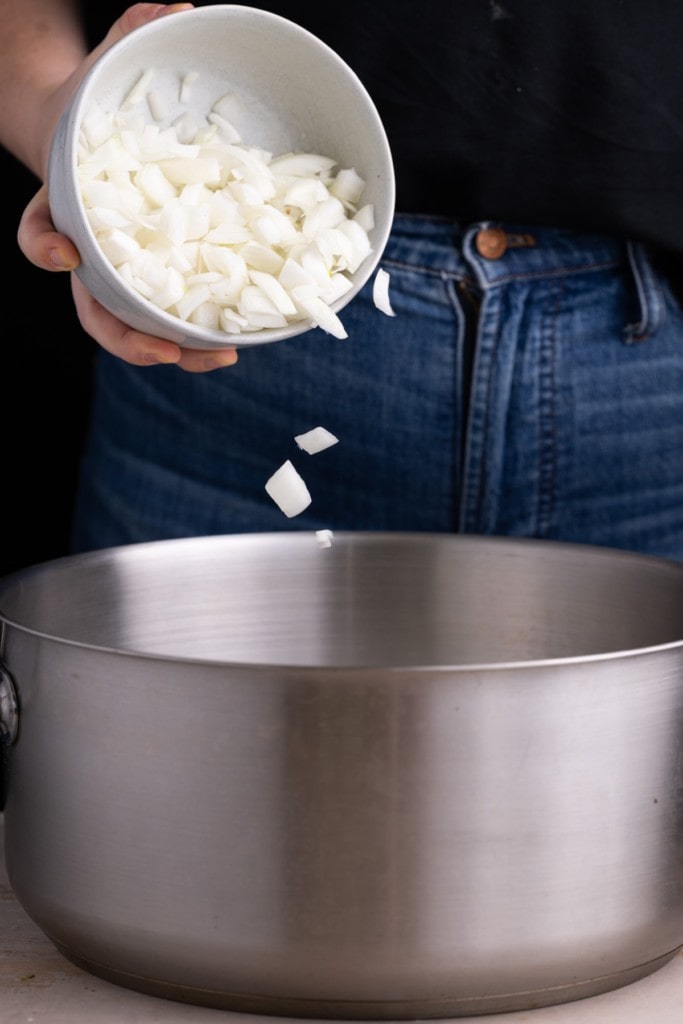 Adding diced onion to a large pot
