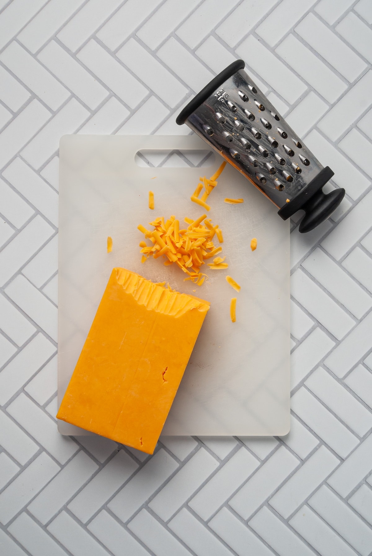 block of cheddar cheese being grated