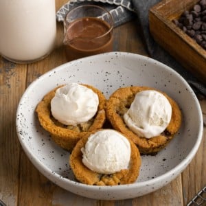 3 cookie dough cups for ice cream in a large shallow bowl with scoops of vanilla ice cream in them