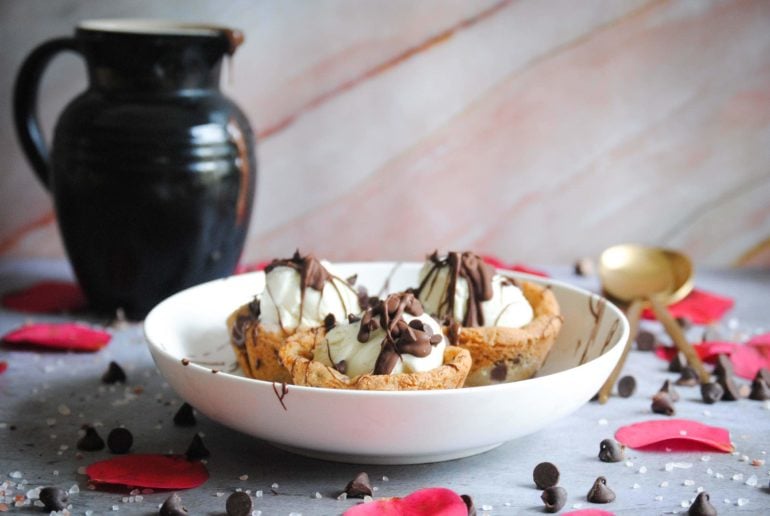 picture of three cookie dough cups for ice cream plated with pitcher behind it