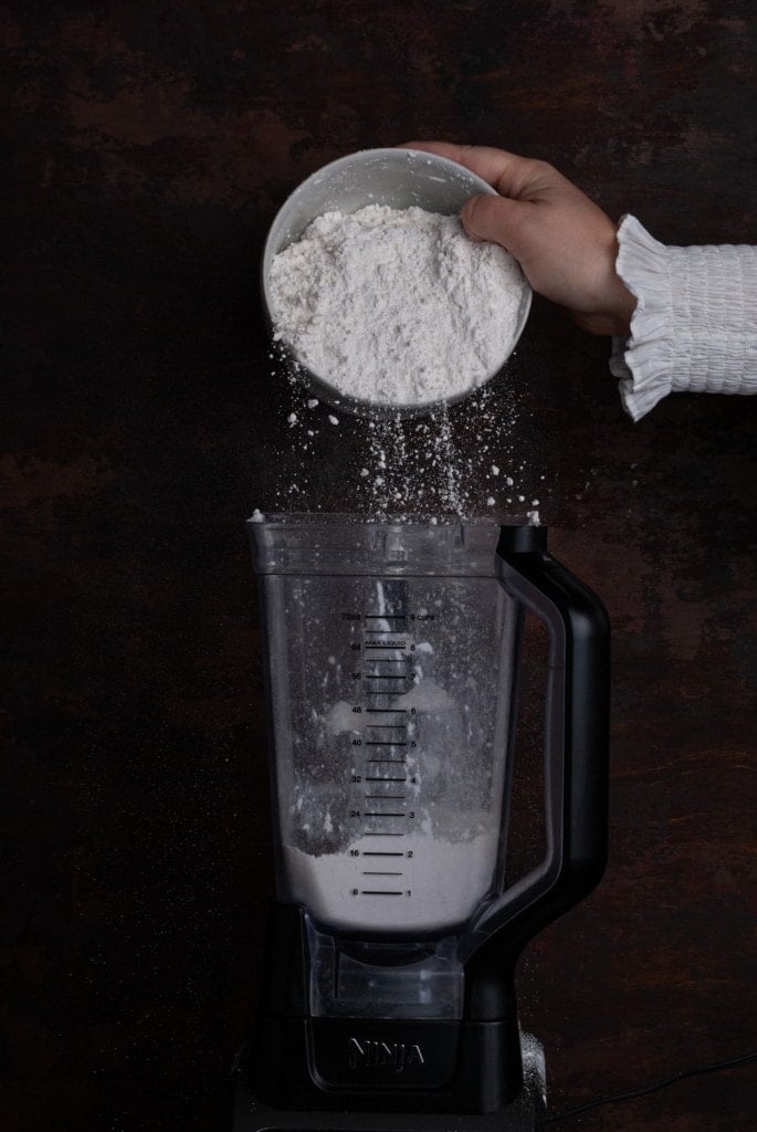 adding flour to a blender to make pie crust