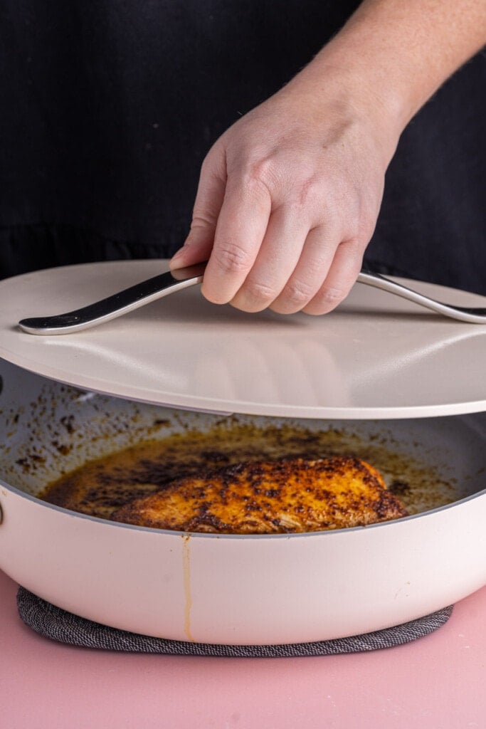 Covering fish while blackening in a pan to avoid oil splatter and to trap heat.