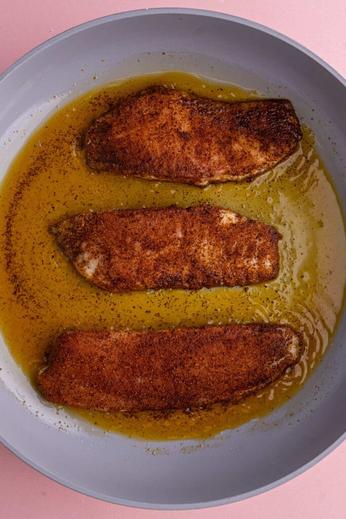 Adding fish coated with taco seasoning to pan with hot coconut oil to blacken. 