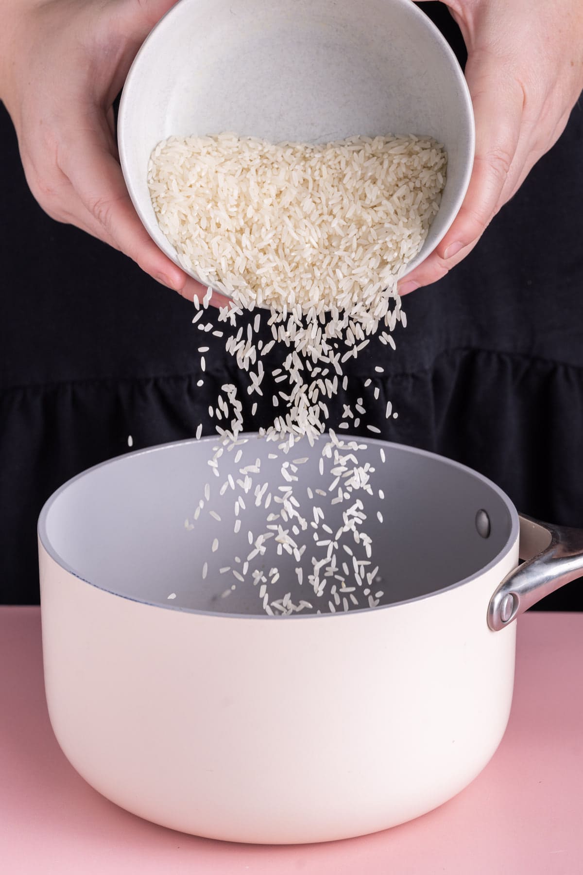 Pouring uncooked rice into a pot to make coconut rice