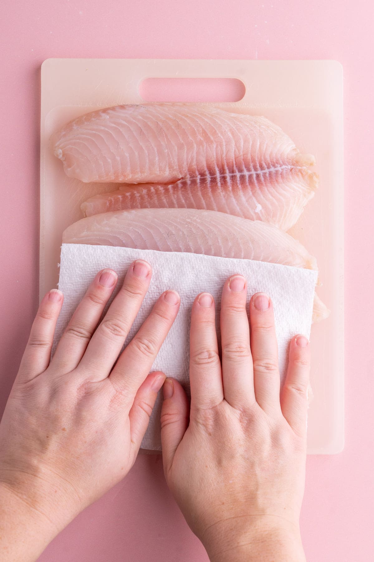 Patting tilapia dry with a paper towel