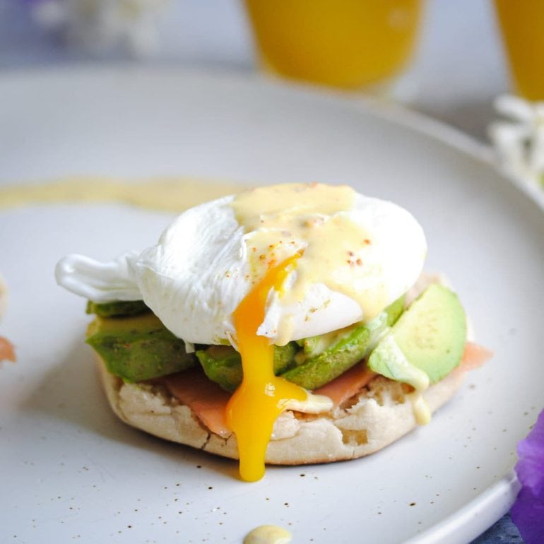 egg yolk dripping out of poached egg over avocado and english muffin