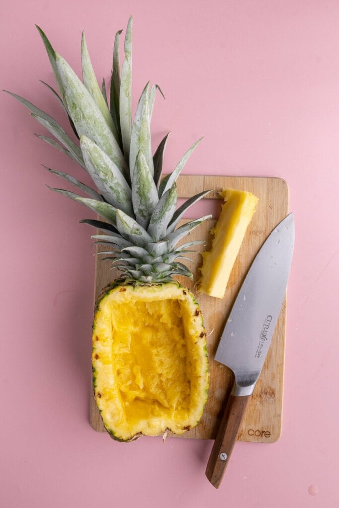 Carving out half of a pineapple to make a bowl for serving Pineapple Pico de Gallo