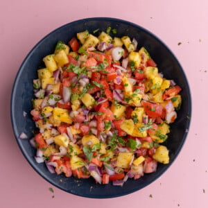 Tossing all pineapple pico de gallo ingredients together in a bowl