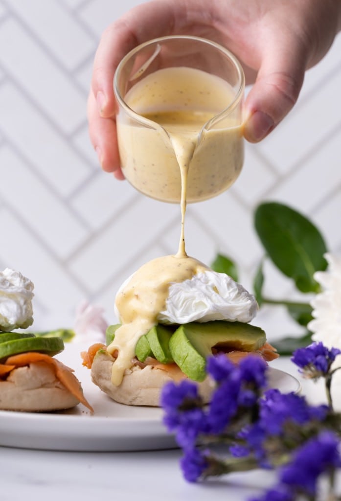 Pouring Hollandaise sauce over Smoked Salmon Eggs Benedict