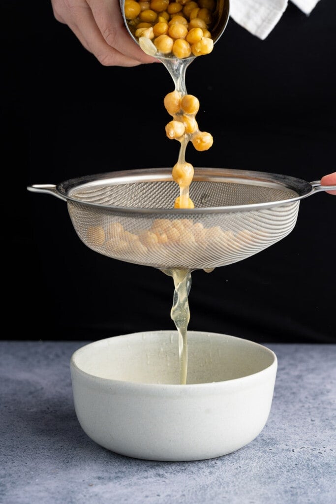 Draining chickpeas and catching aquafaba in a bowl