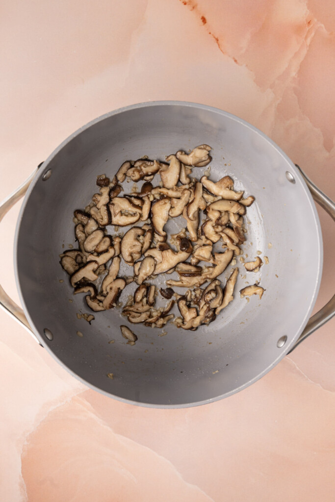 Shitake mushrooms and minced garlic cooked in oil in a large pot. 