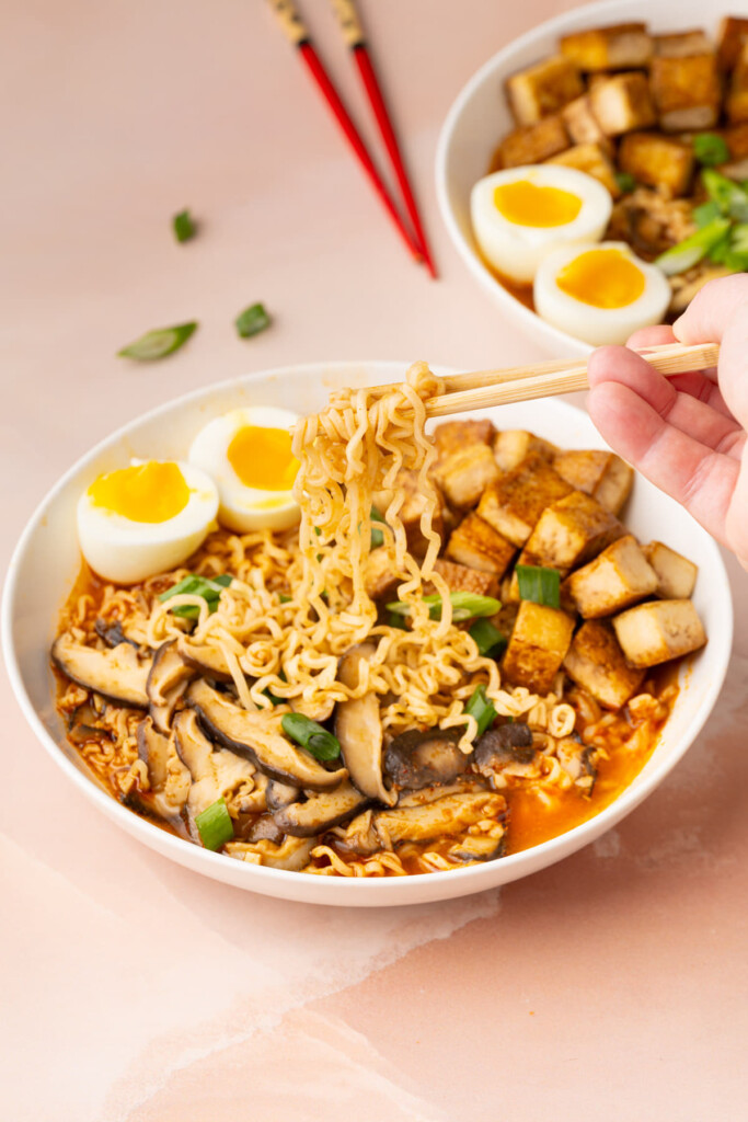 Grabbing ramen noodles with chopsticks out of steaming hot broth.