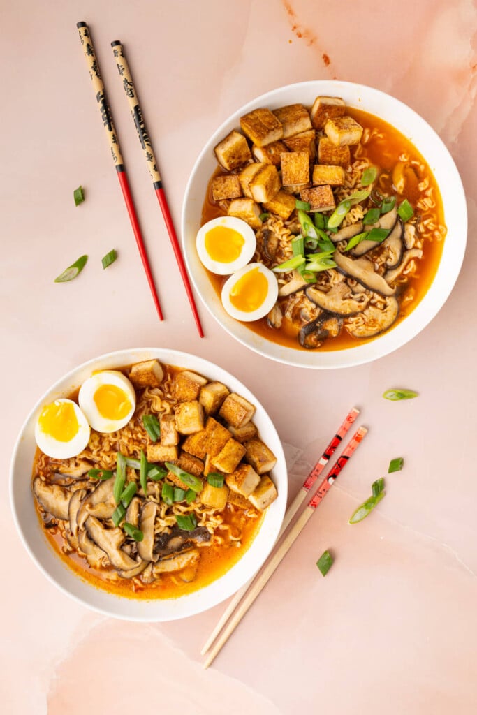 Two bowls of hot ramen with a soft boiled egg, mushrooms, and tofu.