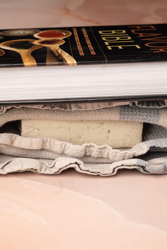 Using a heavy book to press moisture out of tofu without a tofu press. 
