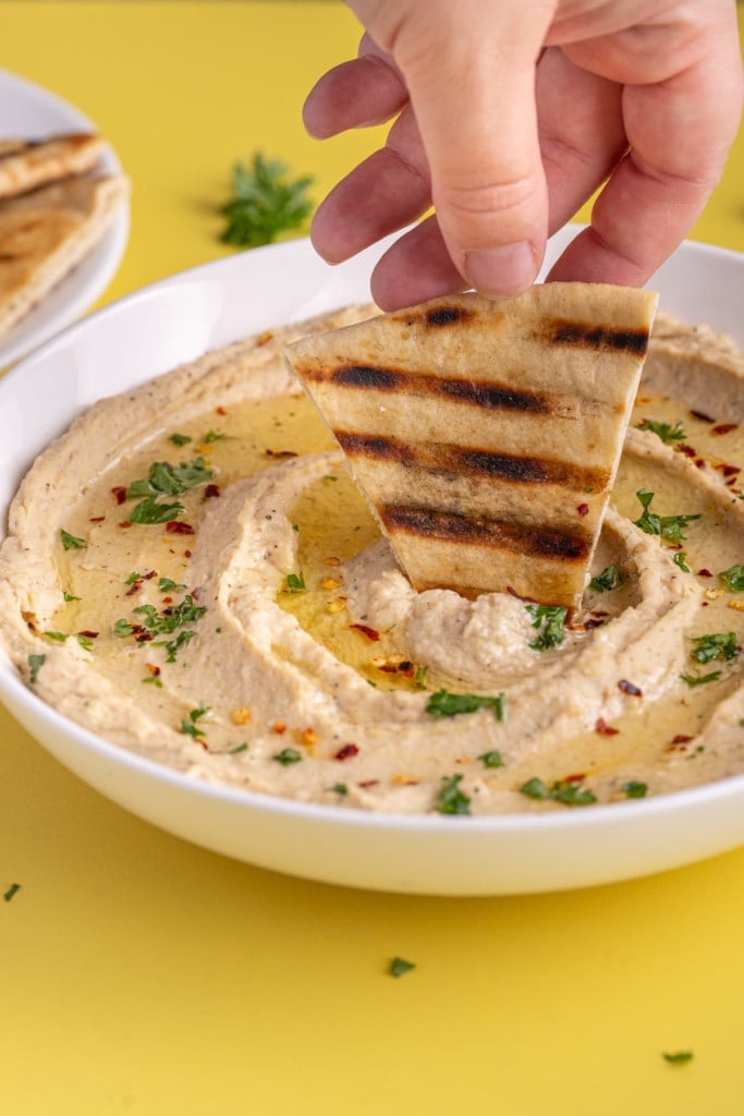 Dipping grilled pit into 5-Minute Hummus