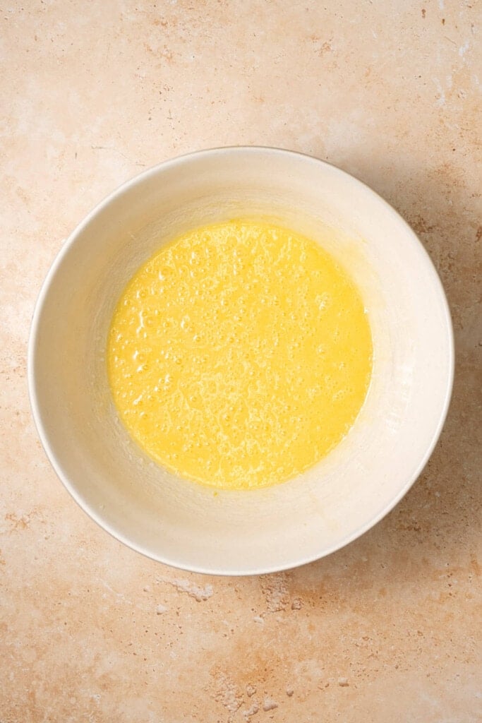 Sugar, eggs, vanilla extract, mayonnaise, and oil whisked together in a large bowl to form the base of a cupcake batter. 
