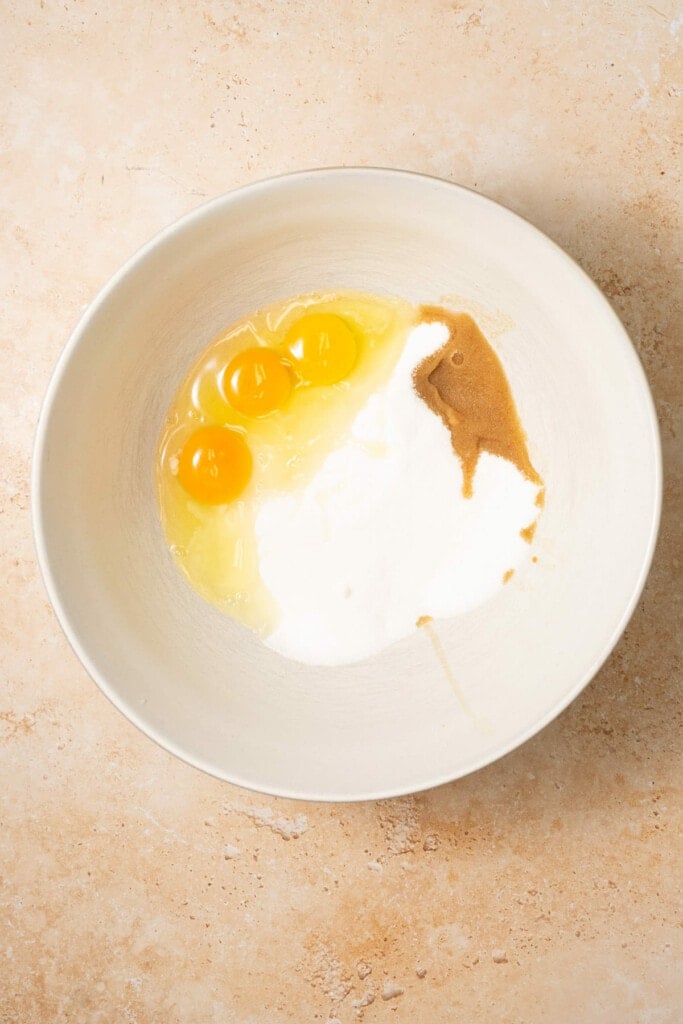 A large mixing bowl with sugar, eggs, and vanilla extract.