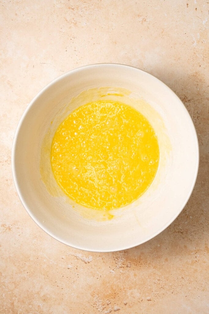 Sugar, eggs, and vanilla extract whisked together in a large mixing bowl. 