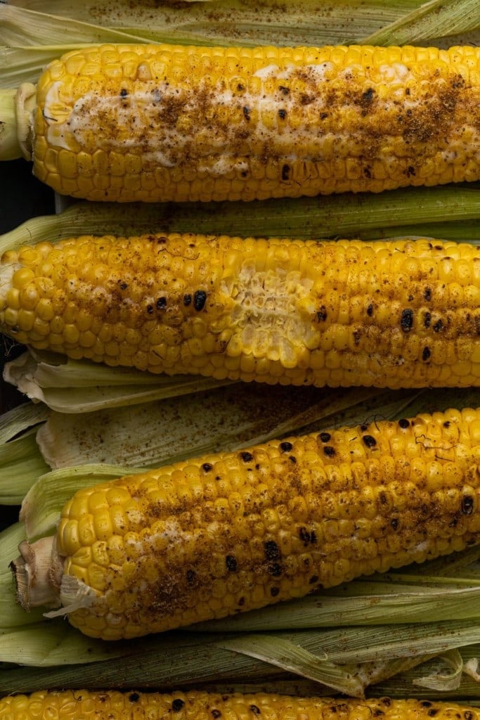 3 ears of grilled old bay corn with one bite taken out of the middle one